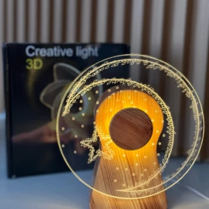 Lámpara 3D giratoria de acrílico con diseño de llave y espiral dorada, montada sobre base de madera, junto a su caja de presentación.