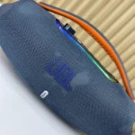 Altavoz portátil JBL Boombox 3 en color azul marino con textura de malla, asa naranja y detalles multicolores en la parte superior.