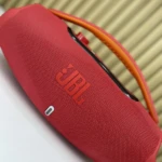 Altavoz portátil JBL Boombox 3 en color rojo, con asa naranja y acabado texturizado, mostrando el logotipo frontal y puerto USB-C lateral.