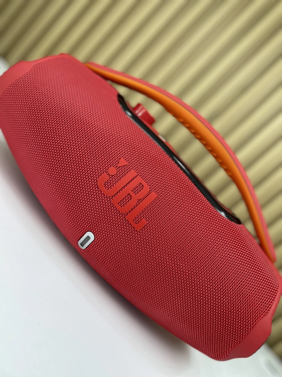 Altavoz portátil JBL Boombox 3 en color rojo, con asa naranja y acabado texturizado, mostrando el logotipo frontal y puerto USB-C lateral.