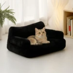 Sofá negro para mascotas con relleno de alta densidad, mostrando un gato acostado sobre su superficie acolchada en ambiente interior.