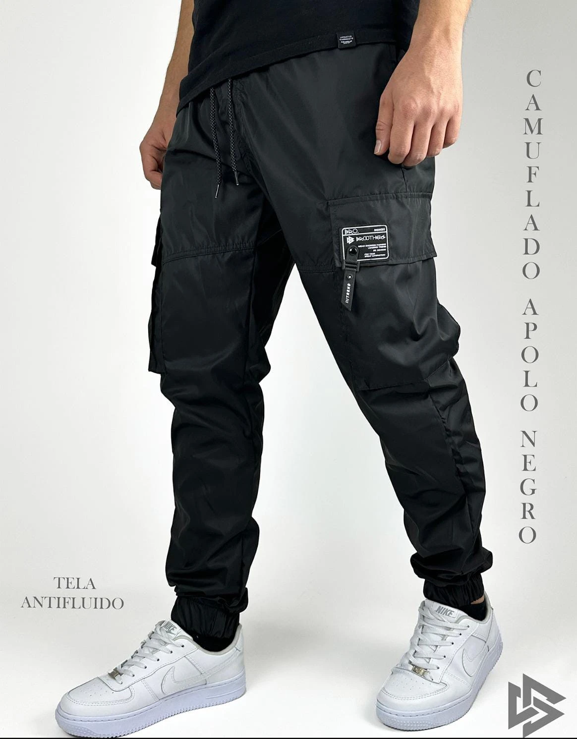 Pantalón negro tipo jogger con múltiples bolsillos, cintura elástica y puños ajustados, sobre fondo blanco.