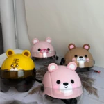 Cuatro cascos infantiles de diseño animal con visor transparente y ajuste seguro, en colores rosa, amarillo y marrón, dispuestos sobre tela clara.