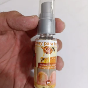 Bote de 20 ml de spray antimicótico con etiqueta que muestra abejas y uñas afectadas, sostenido en mano.