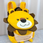 Mochila infantil amarilla con diseño de león, incluye correas de seguridad y detalles en marrón y beige.