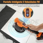 Vibrador de baldosas inalámbrico naranja con pantalla digital y base de goma, en uso sobre azulejo blanco con adhesivo negro.