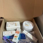 Caja abierta con productos Bioaqua: crema facial, sérum, mascarilla, protector solar y bálsamo labial. Presentación blanca y azul.