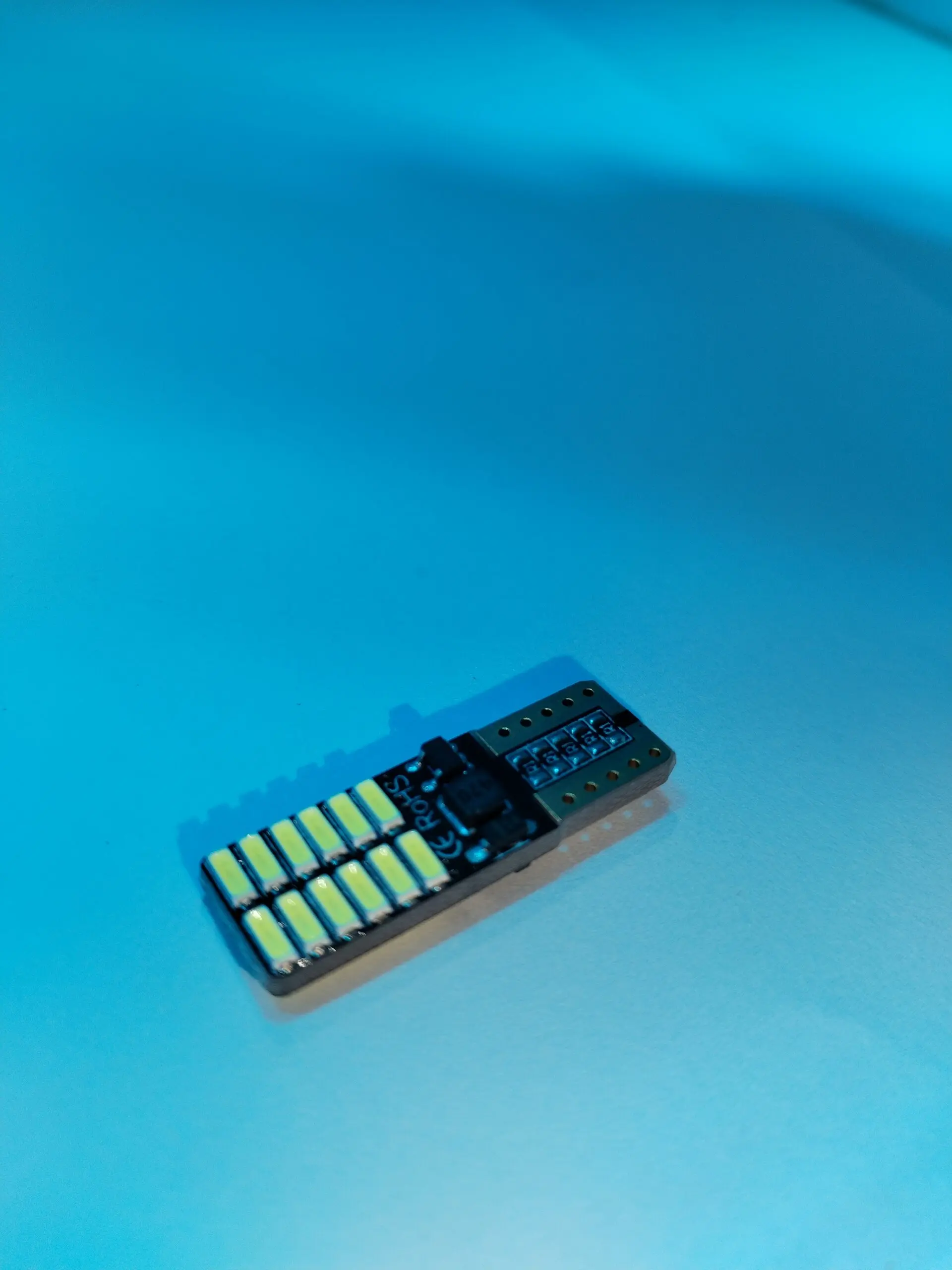 Paleta LED Cocuyo de 12V con 12 diodos amarillos y conector negro, vista lateral sobre fondo azul.