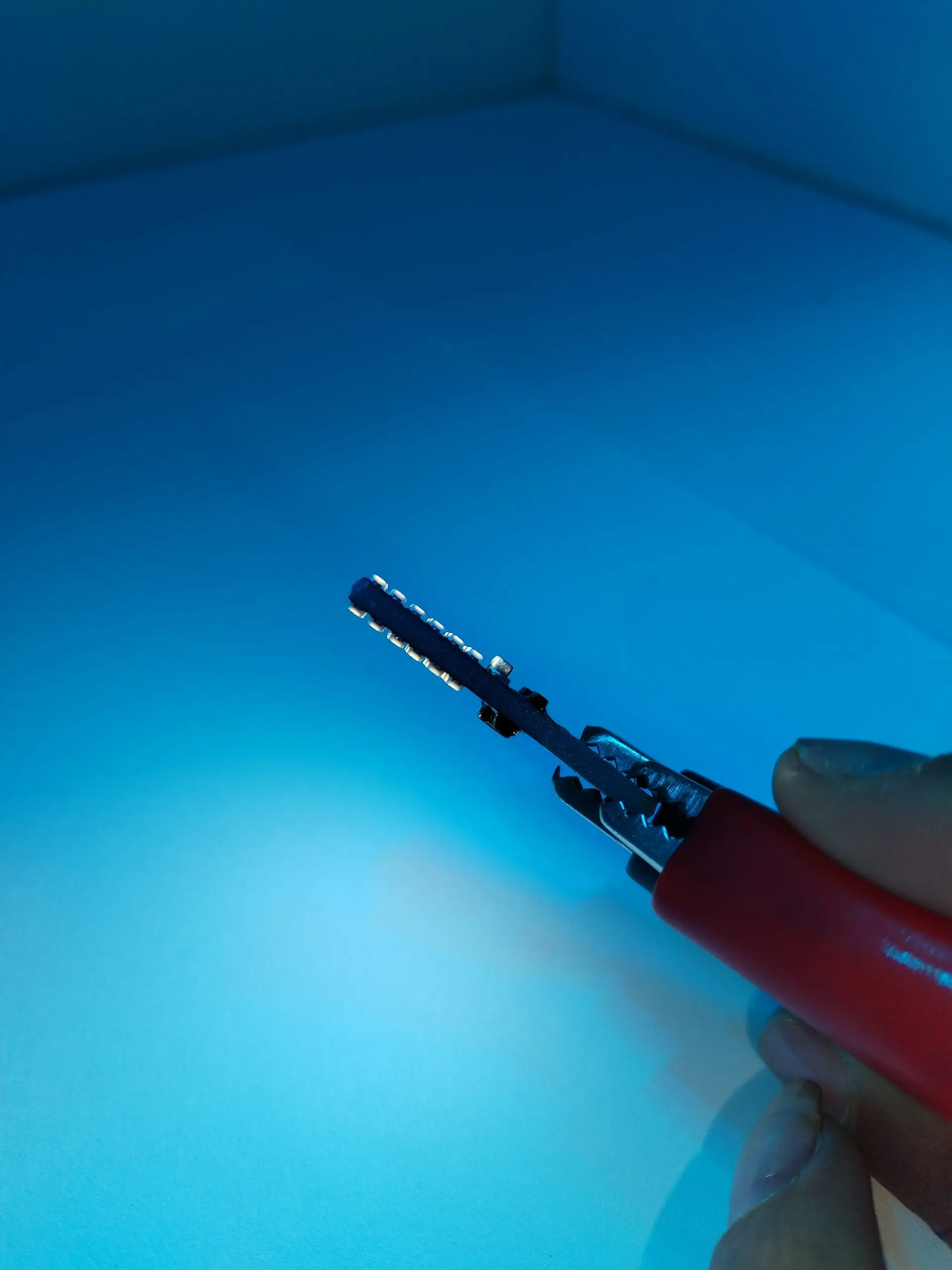 Paleta de luz LED roja con mango ergonómico, emitiendo luz azulada en entorno oscuro, ideal para visibilidad nocturna en vehículos.