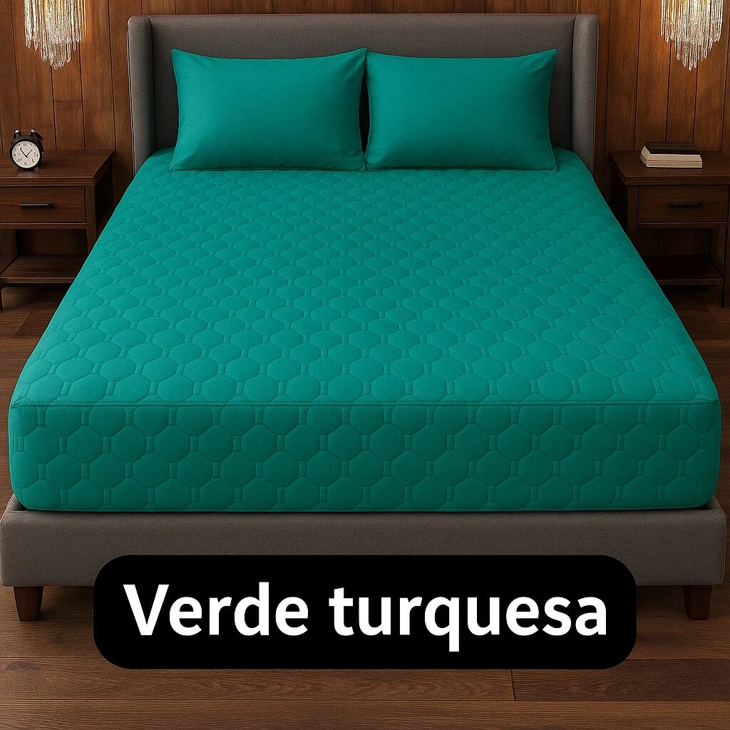 Protector de colchón acolchado en verde turquesa, con textura hexagonal visible, sobre cama con cabecero gris y mesitas de noche.