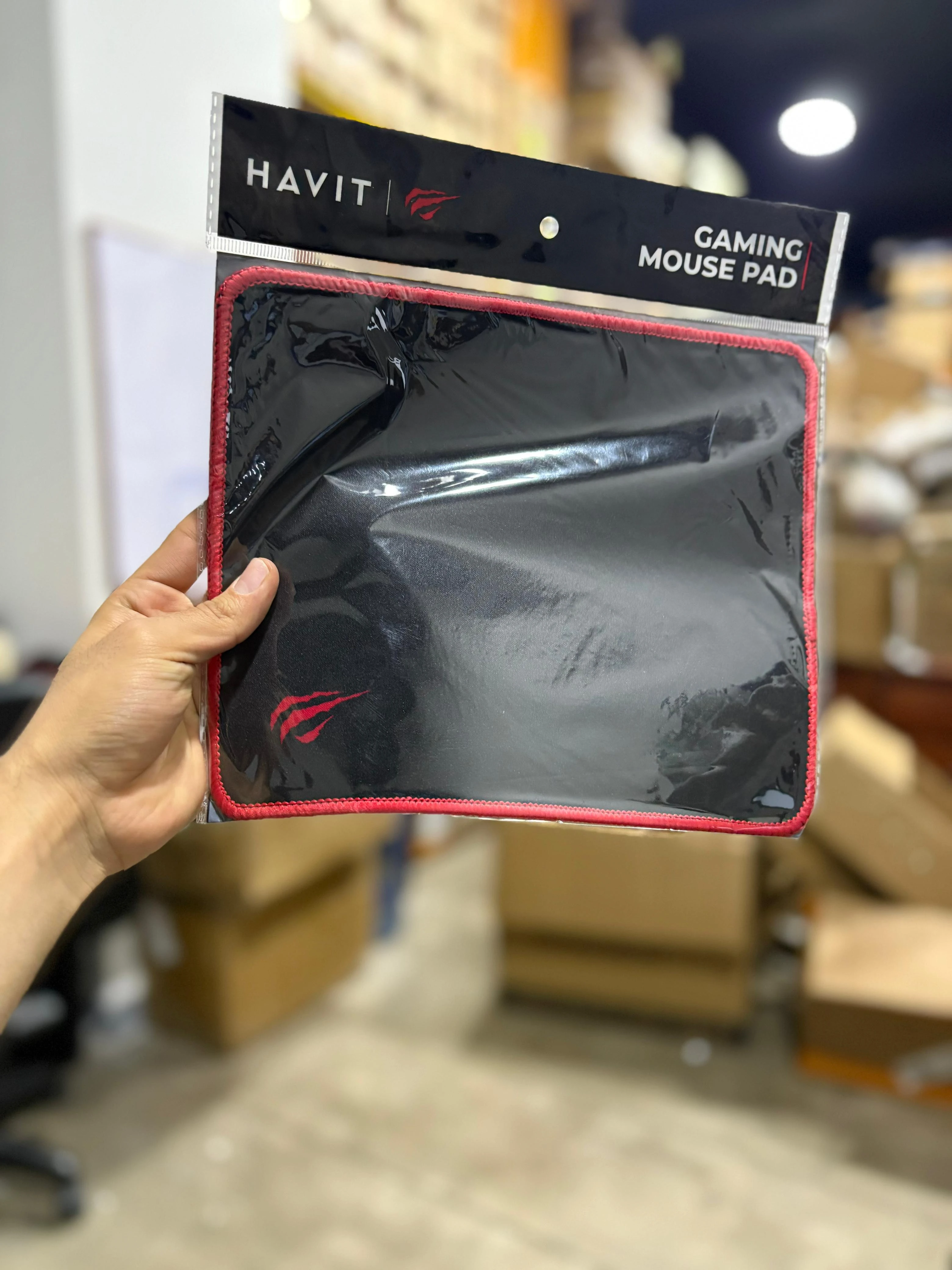 Mousepad cuadrado negro con bordes rojos, marca Havit, en empaque transparente. Ideal para gaming y oficina.