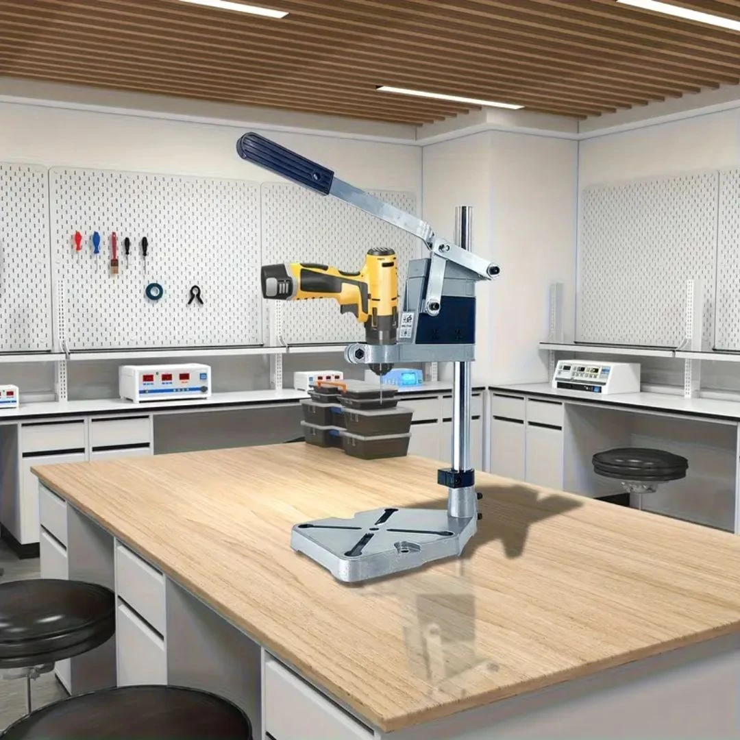 Soporte guía para taladro amarillo y azul sobre mesa de trabajo en laboratorio, con mandril ajustable y regla de profundidad visible.