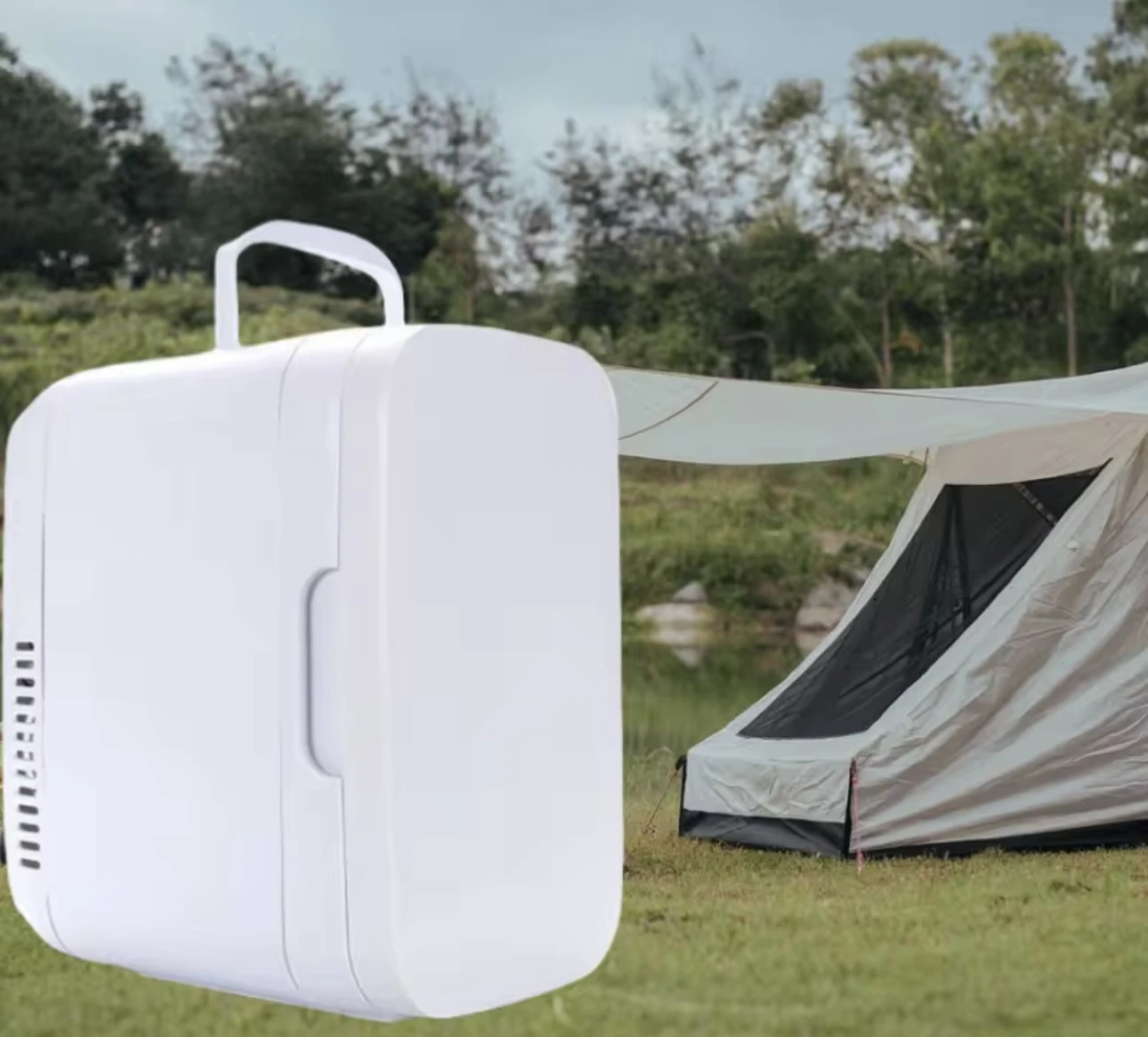 Refrigerador portátil blanco de 8 litros con asa superior y ventilación lateral, sobre césped con carpa al fondo.