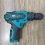 Taladro inalámbrico Makita 1802 en color turquesa y negro, visto desde arriba sobre superficie de madera.
