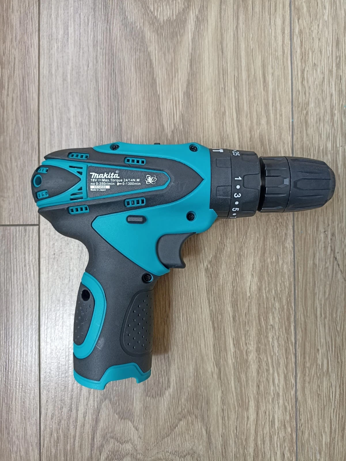Taladro inalámbrico Makita 1802 en color turquesa y negro, visto desde arriba sobre superficie de madera.