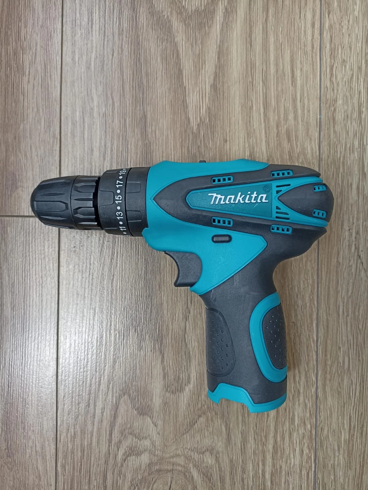 Taladro inalámbrico Makita 1802 en color azul y negro, con mango ergonómico y chasis de goma antideslizante, sobre superficie de madera clara.