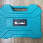 Caja de transporte azul Makita con asas y cierre rojo, sobre superficie de madera.