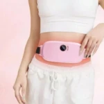 Cinturón de masaje térmico rosa con control digital, usado en la cintura de una mujer con ropa deportiva blanca.