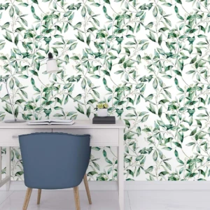 Papel adhesivo decorativo mate con patrón de hojas verdes sobre fondo blanco, aplicado en pared trasera de escritorio moderno con silla azul y accesorios minimalistas.