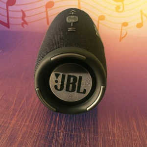 Parlante JBL Charge 5 negro sobre superficie de madera, con detalles en gris y fondo musical.