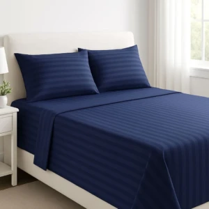 Sábana de polialgodón 600 hilos en azul marino con rayas finas, presentada sobre cama blanca con cojines a juego.