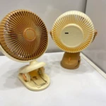 Dos ventiladores mini portátiles en tonos beige y marrón, con rejillas circulares y base de sujeción tipo pinza, mostrando frontal y trasera.