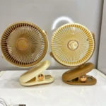Dos ventiladores mini portátiles de color beige y marrón, con diseño circular y base de sujeción tipo pinza, dispuestos sobre superficie blanca.