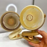 Dos ventiladores mini portátiles con clip, uno en tono beige y otro en marrón claro, mostrando su diseño circular con rejilla protectora y logotipo central.