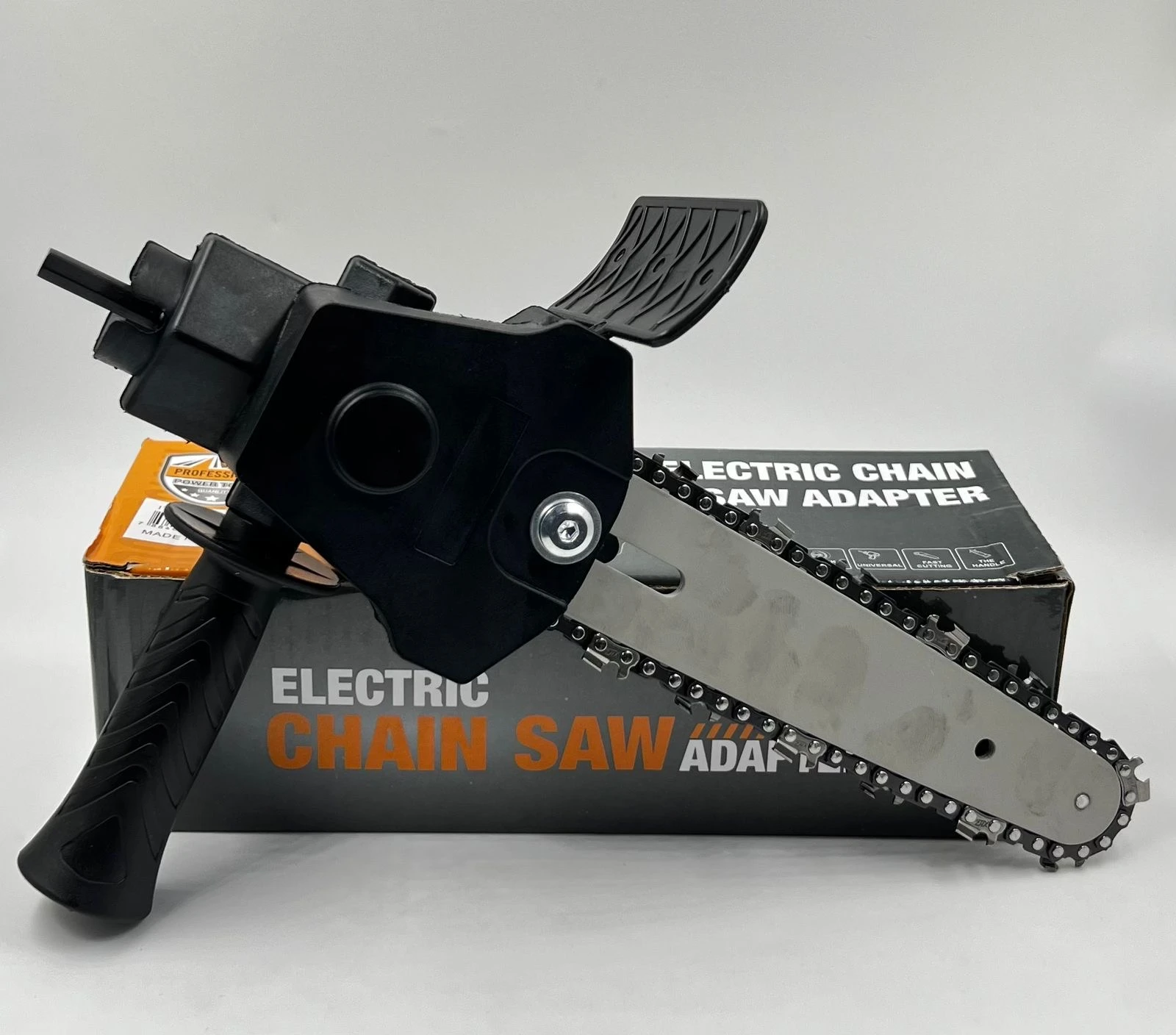 Adaptador negro para taladro con cadena de sierra y guarda de seguridad, sobre caja que indica "Electric Chain Saw Adapter".