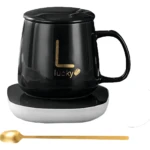 Termo eléctrico de cerámica negro con base calefactora blanca, asa integrada, tapa ajustable y logo dorado "Lucky". Incluye cuchara dorada.