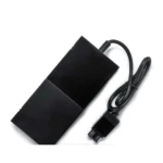 Fuente de alimentación externa para Xbox One en color negro, con cable enrollado y conector visible.