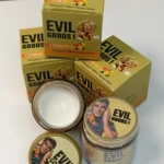 Pack de crema hidratante Evil Goods en presentación de caja y tarro abierto, con tapa y envase cerrado. Diseño en tonos dorados y amarillos, de Marilyn Monroe y modelo masculino. Incluye etiqueta "Citrus" y texto "Whipped Tallow Honey Balm".