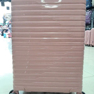 Maleta de cabina rosa con ruedas giratorias y diseño de líneas horizontales, vista frontal en tienda.