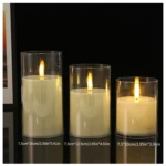 Set de tres velas LED sin llama en vidrio transparente, de diferentes alturas (15 cm, 12.5 cm y 10 cm), con llama simulada encendida sobre fondo negro.