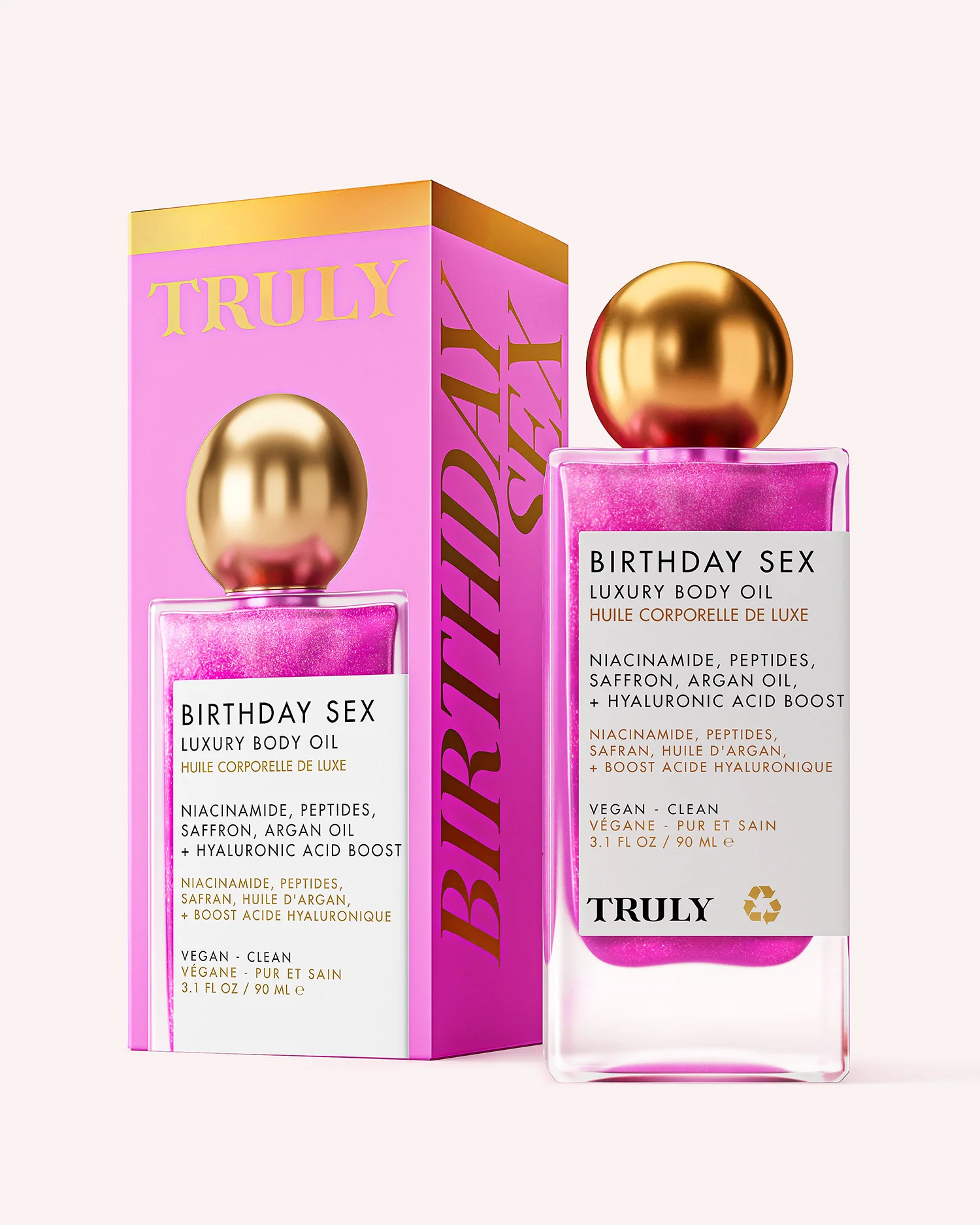 Botella de aceite corporal Truly Birthday Sex en color rosa con detalles dorados, junto a su caja. Etiqueta indica ingredientes como niacinamida, safrán y ácido hialurónico. Presentación vegana y limpia.