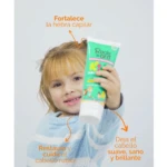 Tubo de mascarilla restauradora para cabello rubio de niños, con manzanilla y argán. Presentación verde con ilustraciones de flores y niños. Texto en español sobre beneficios: fortalece hebra capilar, restaura y cuida cabello rubio, deja cabello suave, sano y brillante.