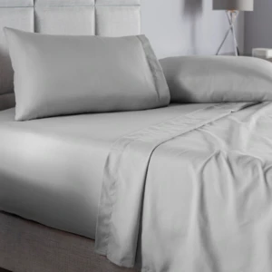 Juego de sábanas gris claro queen liso, con acabado suave y moderno, mostrando colchón, almohadas y sábanas dobladas en cama con cabecero tapizado.