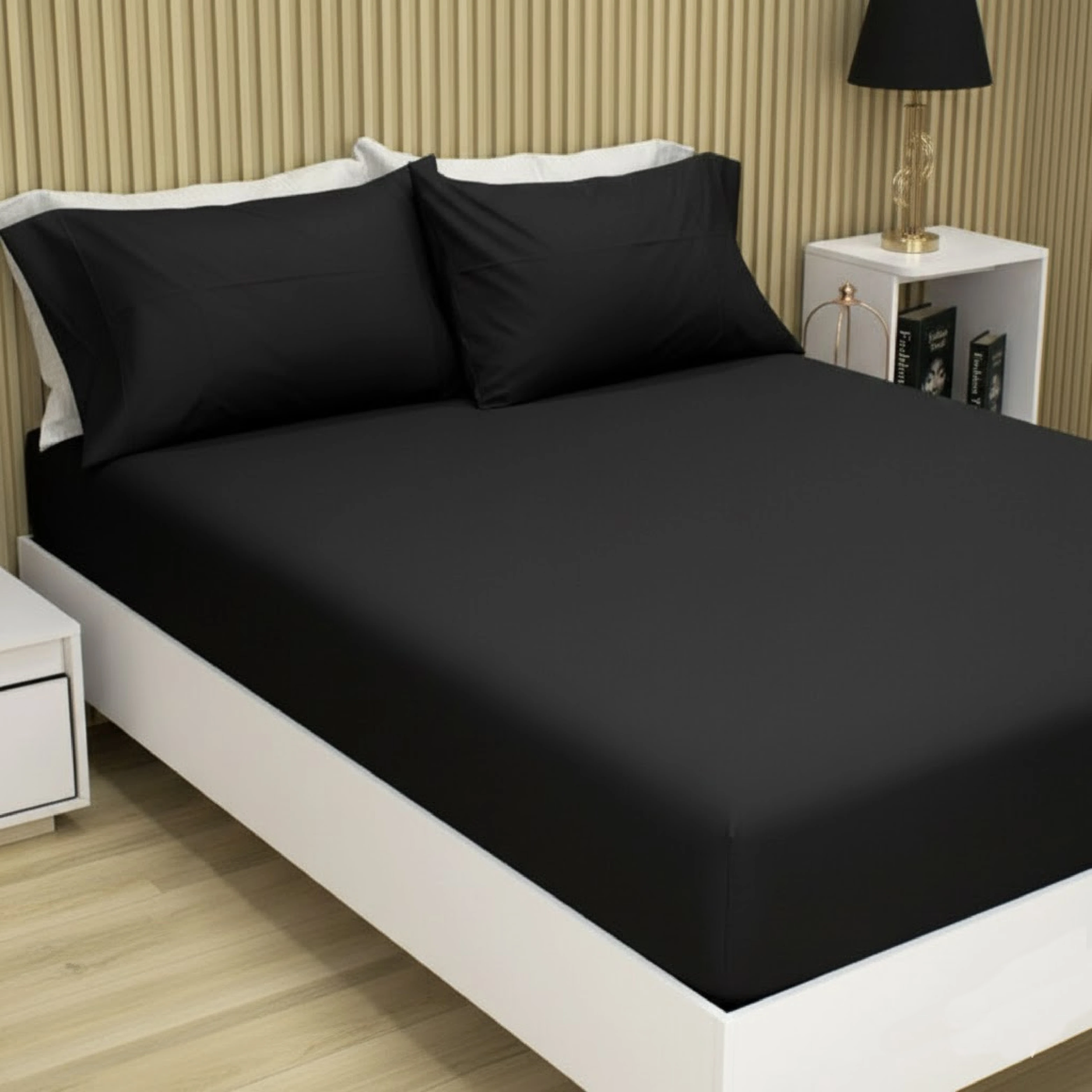 Sábana ajustable negra con dos fundas de almohada, vista frontal en cama blanca sobre suelo de madera clara.