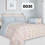 Plumón estampado floral en tonos pastel sobre cama con cabecero blanco y cojines a juego, vista frontal completa.