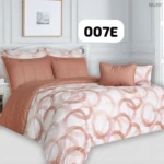 Plumón con estampado geométrico en tonos rosados sobre fondo blanco, acompañado de cojines y funda de almohada a juego, exhibido en cama con cabecero blanco y decoración minimalista.