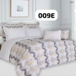 Plumón con estampado geométrico en tonos beige, gris y blanco, sobre cama con cabecero blanco y cojines combinados.