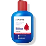 Botella azul de 300 ml de champú Nippori anti caspa con tapa roja, etiqueta blanca con texto negro y rojo, gota roja decorativa y lista de beneficios en azul.