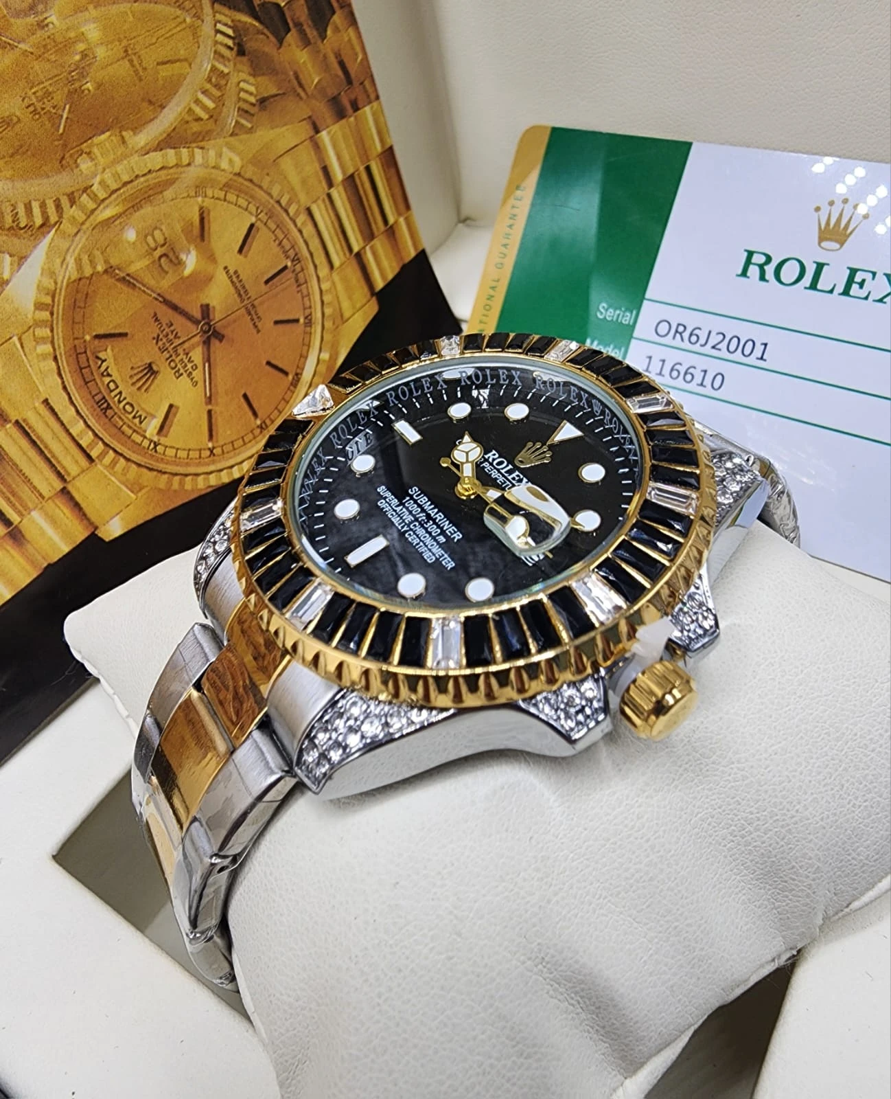 Reloj Rolex de lujo con esfera negra, bisel dorado y detalles de diamantes, sobre soporte blanco con tarjeta de garantía visible.