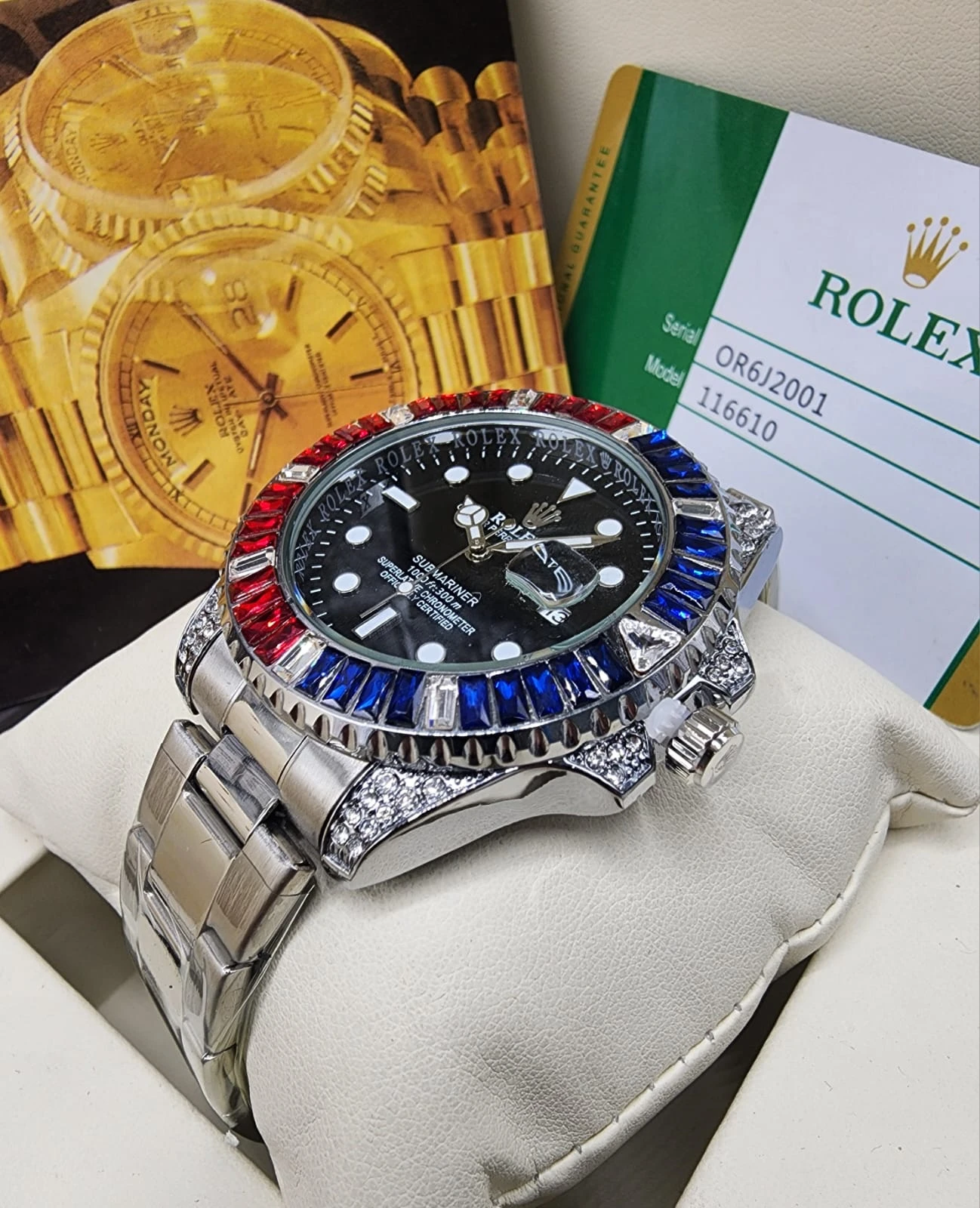 Reloj de lujo con esfera negra, bisel multicolor en rojo, azul y verde, y detalles de zafiro. Incluye caja de presentación con tarjeta Rolex.