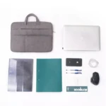 Maletín acolchado gris para laptop, con funda protectora, portafolios, mouse, cargador y accesorios organizados sobre fondo blanco.