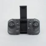 Control remoto negro para cuadricóptero plegable con cámara HD, mostrando palancas de mando, botones de función y antena desplegable.