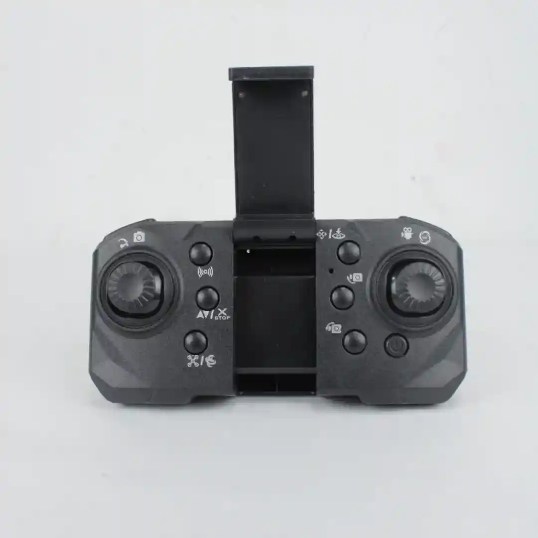 Control remoto negro para cuadricóptero plegable con cámara HD, mostrando palancas de mando, botones de función y antena desplegable.