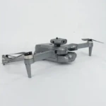 Cuadricóptero plegable gris con cámara frontal y sensores laterales, diseñado para grabación aérea y navegación segura.