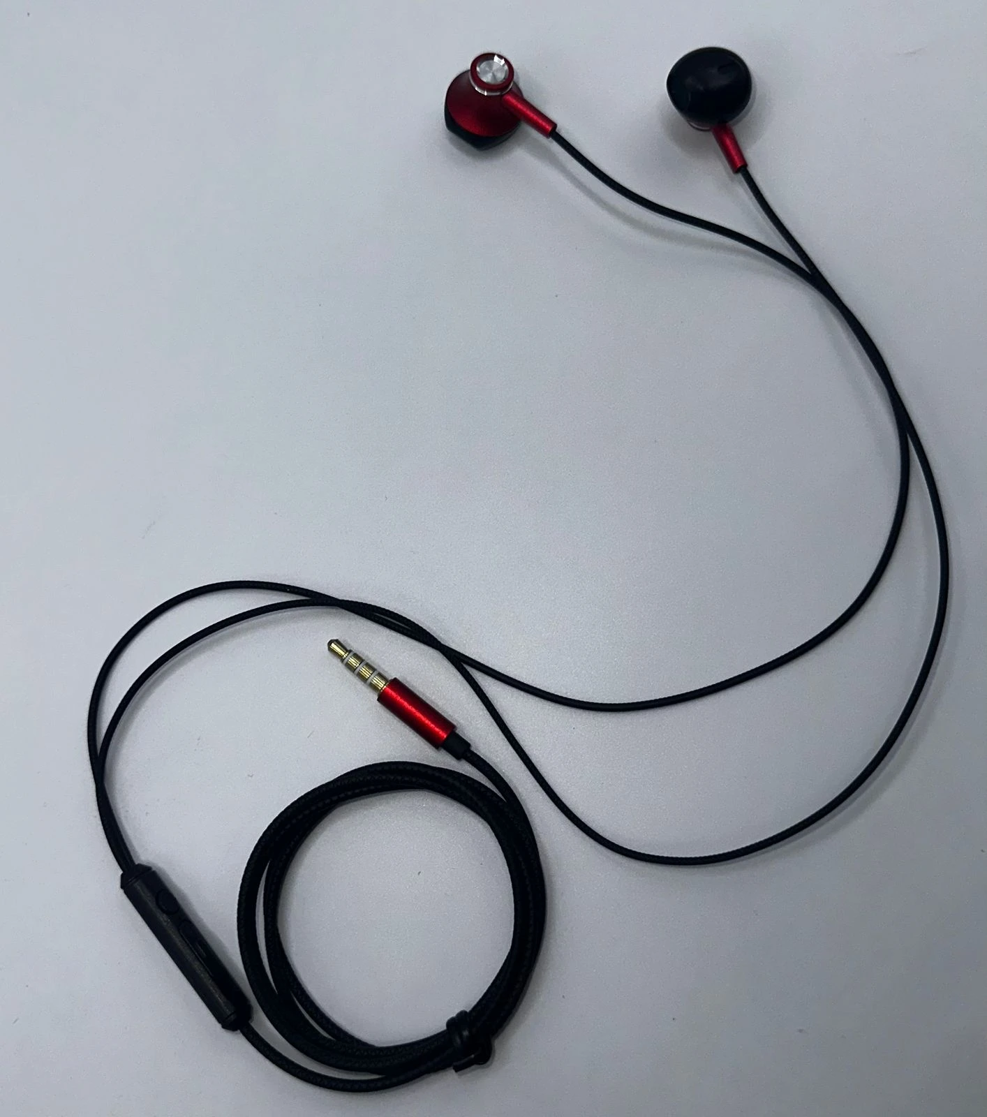 Auriculares intrauditivos con cable negro y detalles en rojo, con micrófono integrado y conector de 3.5 mm.