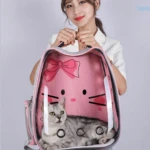 Mochila tipo cápsula rosa con estampado Hello Kitty, transparente y ventilada, con gato gris dentro; ideal para transporte seguro de mascotas hasta 12 kg.